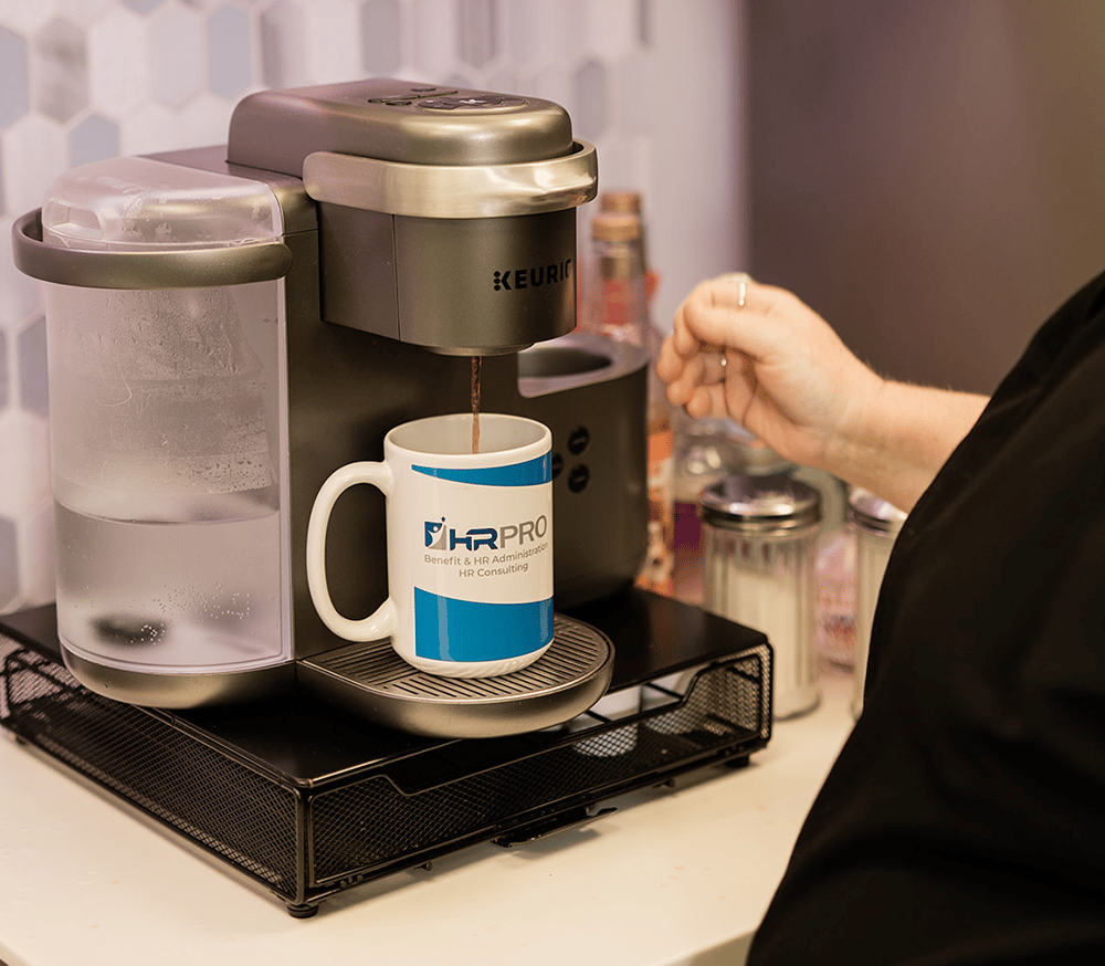 A woman pouring coffee into an HR Pro mug